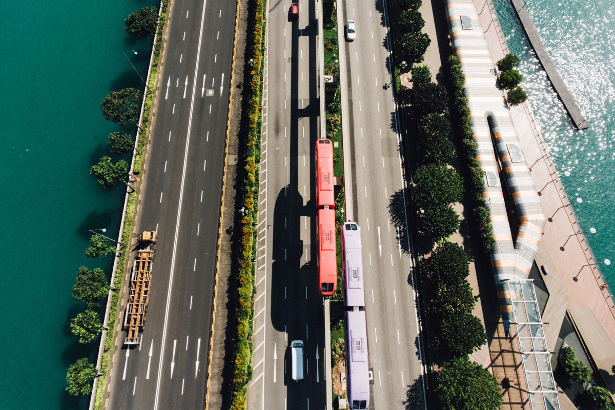 drone shot of singapore trains next to busy road