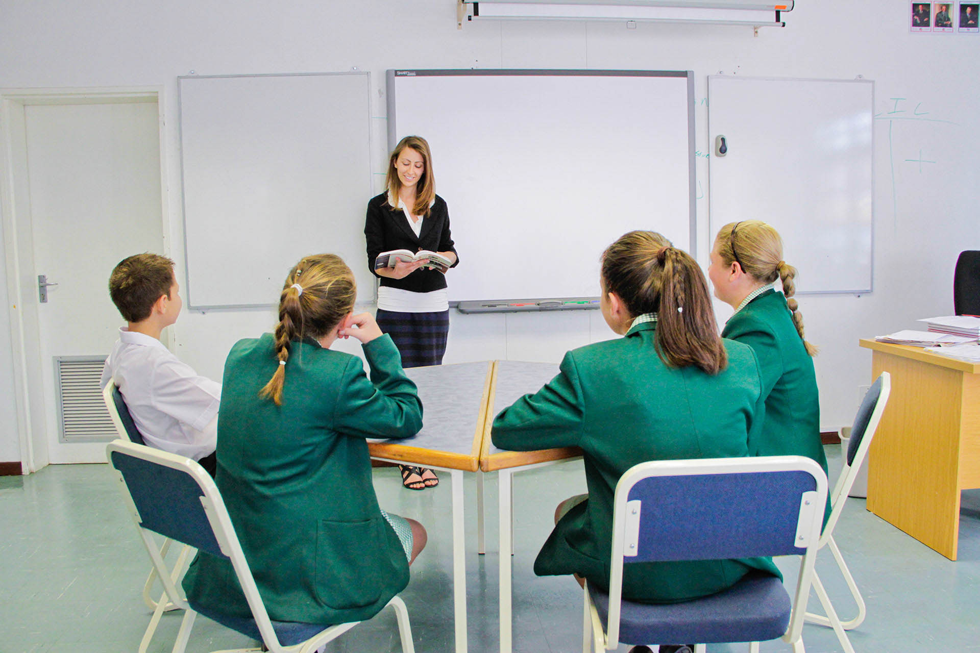 Teacher at the front of a classroom taking to students 